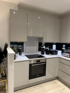uma cozinha com armários brancos e um forno com placa de fogão em Beautiful 3 Bedroom Duplex Apartment with Balcony em North Woolwich