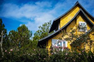 a yellow house with flowers in front of it at Binh An Village Resort in Da Lat