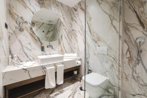 a marble bathroom with a sink and a shower at Bristol Hotel Podgorica in Podgorica