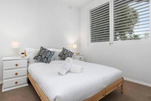 a white bedroom with a bed and a window at Tranquil apartment in the city in Newcastle