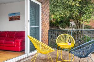 two chairs and a yellow table on a porch with a red couch at Tranquil apartment in the city in Newcastle