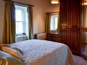 a bedroom with a bed and a dresser and windows at Primrose Villa in Rosedale Abbey