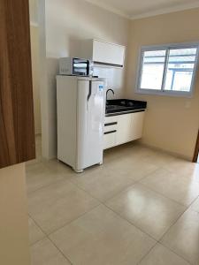 a kitchen with a white refrigerator and a window at KITNET 1001 Apart Hotel in Piracicaba