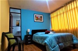 1 dormitorio azul con 1 cama y 1 silla en Hostal Los Pinos, en Huancayo