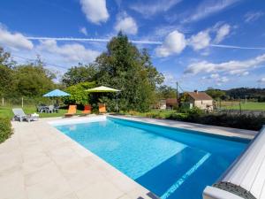a swimming pool in a yard with chairs and umbrellas at Gîte Montignac, 4 pièces, 6 personnes - FR-1-616-83 in Montignac