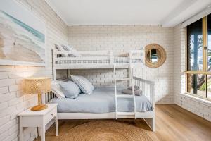 een slaapkamer met witte stapelbedden en een spiegel bij Surfers Reserve Beachfront - WIFI- Family friendly in Middleton