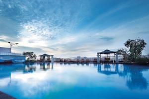 a large pool of blue water with two gazebos at Regal Palace Hotel in Dongguan