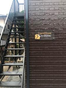 una escalera con una señal en el lateral de un edificio de ladrillo en Guest House Kiyohime, en Tanabe