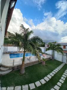 a patio with palm trees and a swimming pool at Recanto Familiar in Monte das Gameleiras