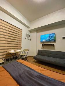 ein Wohnzimmer mit einem Sofa und einem TV an der Wand in der Unterkunft The Nearest Studio from MactanAirport with Disney+ in Pusok