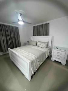 a bedroom with a white bed and a white dresser at Residencial joyas d’ luxe lll in Santiago de los Caballeros