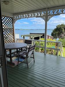 una terraza de madera con mesa y mesa de picnic en Tamaterau Seaview House in Whangarei, en Whangarei
