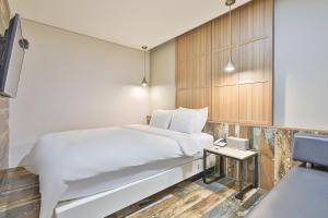 um quarto com uma cama branca e uma mesa lateral em Gracias Hotel Gimhae em Gimhae