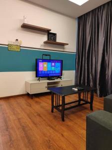 uma sala de estar com uma televisão e uma mesa de centro em H. S. Tang's Homestay J1 em Kuching