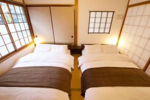 2 Betten in einem Zimmer mit Fenstern in der Unterkunft push house 伊東 in Ito