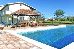 uma piscina com cadeiras e um gazebo ao lado de uma casa em Apartments Lug 2 new and comfortable with pool em Privlaka