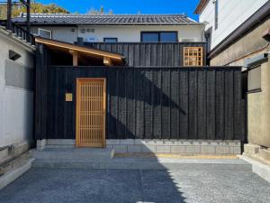 倉敷市にある暮らしの宿てまり まどろみの家の前に木製の扉を持つ黒い柵