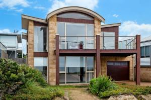 a large house with a balcony and glass at Aqua Luna in Port Fairy