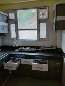 a kitchen with a sink and a window with a clock at Mahamaya Homestay 4 in Mandi