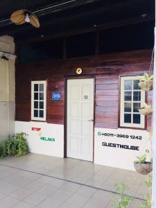 un edificio de madera con puerta blanca y 2 ventanas en Stop @Melaka Guesthouse, en Melaka