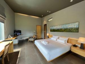 a bedroom with a large white bed and a desk at Teras Hotel Ijen Banyuwangi in Banyuwangi