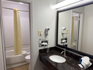 uma casa de banho com um lavatório, um espelho e um WC. em Americas Best Value Inn Austin em Austin