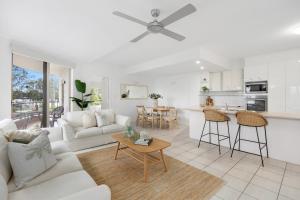a white living room with a couch and a table at Como Noosa in Noosaville