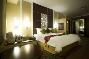 a hotel room with a large bed and a table at Emerald Garden International Hotel in Medan