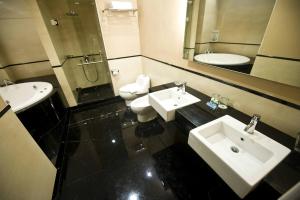 a bathroom with two sinks and a mirror and two toilets at Emerald Garden International Hotel in Medan