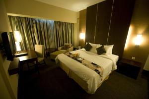 a hotel room with a large bed and a desk at Emerald Garden International Hotel in Medan