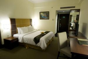 a hotel room with a large bed and a desk at Emerald Garden International Hotel in Medan