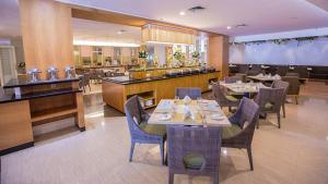 a restaurant with tables and chairs and a bar at Emerald Garden International Hotel in Medan