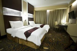 a hotel room with two beds and a television at Emerald Garden International Hotel in Medan