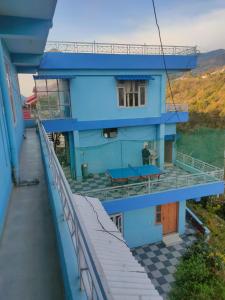 Ein blaues Gebäude mit einem Balkon, auf dem ein Mann steht. in der Unterkunft Mahamaya Homestay 4 in Mandi