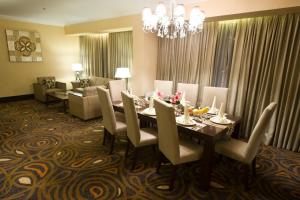 a dining room with a table and chairs and a couch at Emerald Garden International Hotel in Medan