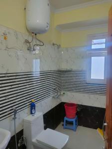 bagno con servizi igienici bianchi e sgabello rosso di Mahamaya Homestay 4 a Mandi