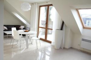 a white dining room with a white table and chairs at Apartament Morski in Rewal