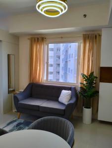 ein Wohnzimmer mit einem Sofa und einem großen Fenster in der Unterkunft Cozy Flexi 1BR or 2BR condo at Southmall Las Pinas in Manila