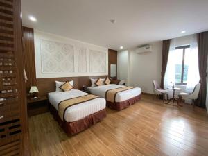 Ðục Khê的住宿－ĐTT Galaxy Tam Chúc，酒店客房带两张床和一张桌子以及椅子。
