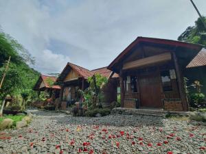 a house with red flowers on the ground in front of it at Lucky Bamboo'Bungalows and Orangutan Jungle Trekking Tours in Bukit Lawang