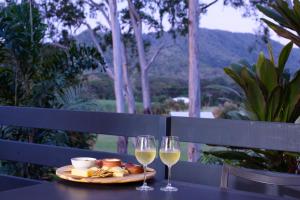 a table with two glasses of white wine and food at Big4 Port Douglas, Glengarry Holiday Park in Port Douglas
