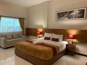 a bedroom with a large bed and a couch at Kuta Suci Guesthouse in Kuta