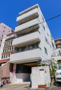 un grand bâtiment blanc avec une voiture garée devant. dans l'établissement 自由自在OSU 501(SORA), à Nagoya