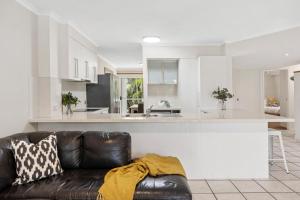 a living room with a couch and a kitchen at Sunset Cove Noosa in Noosaville