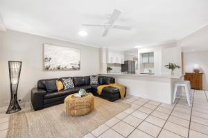 a living room with a black couch and a kitchen at Sunset Cove Noosa in Noosaville