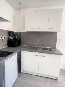 a kitchen with white cabinets and a sink at SUPER Studio Tout équipé WIFI 2PERS in Saint-Quentin