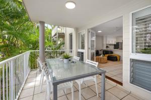 a glass table and chairs on a balcony at Sunset Cove Noosa in Noosaville
