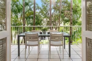 a table and chairs on a patio with palm trees at Sunset Cove Noosa in Noosaville