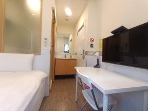 台北市にあるカラーミックス ホテル & ホステルのベッド、デスク、テレビが備わる客室です。