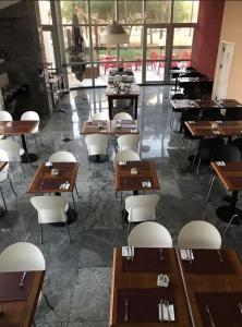 um restaurante com mesas de madeira e cadeiras brancas em Unidade Executiva Luxo 33m² em Brasília